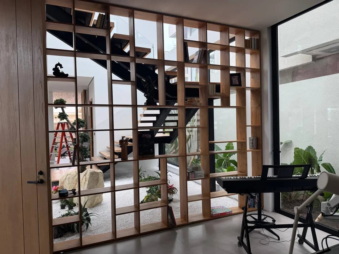 Full-height teak shelving partition beside an indoor garden