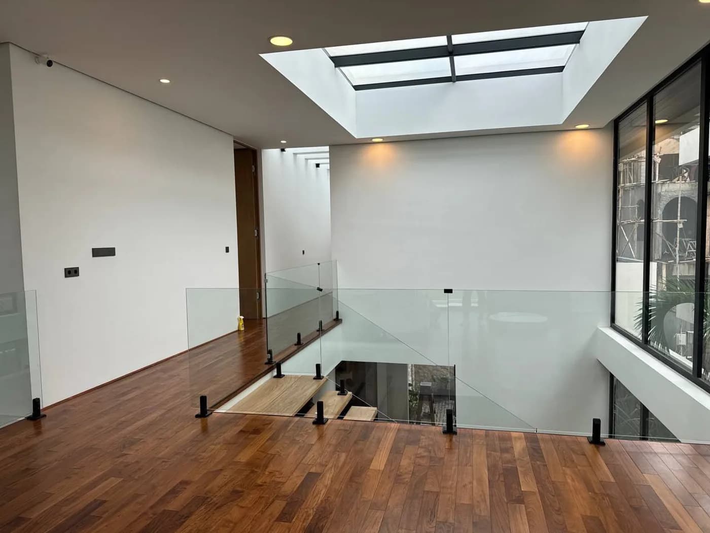 Teak floor landing with glass balustrade under a skylight
